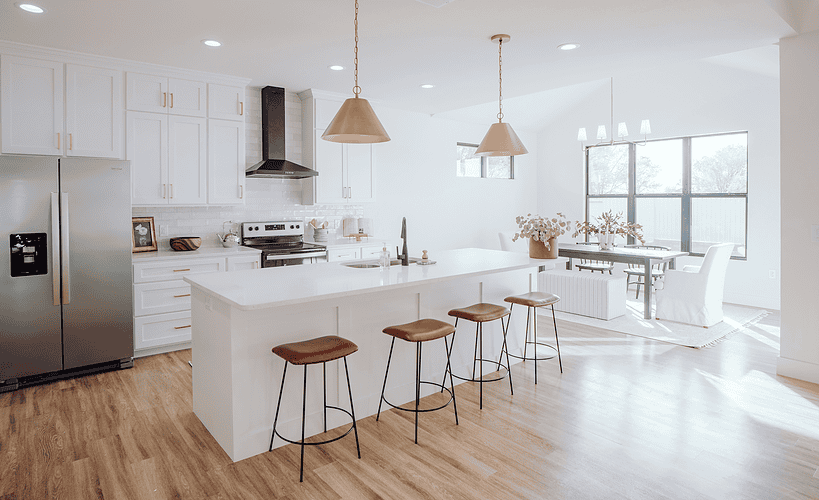 Modern kitchen with warm wood flooring, large island and neutral cabinetry